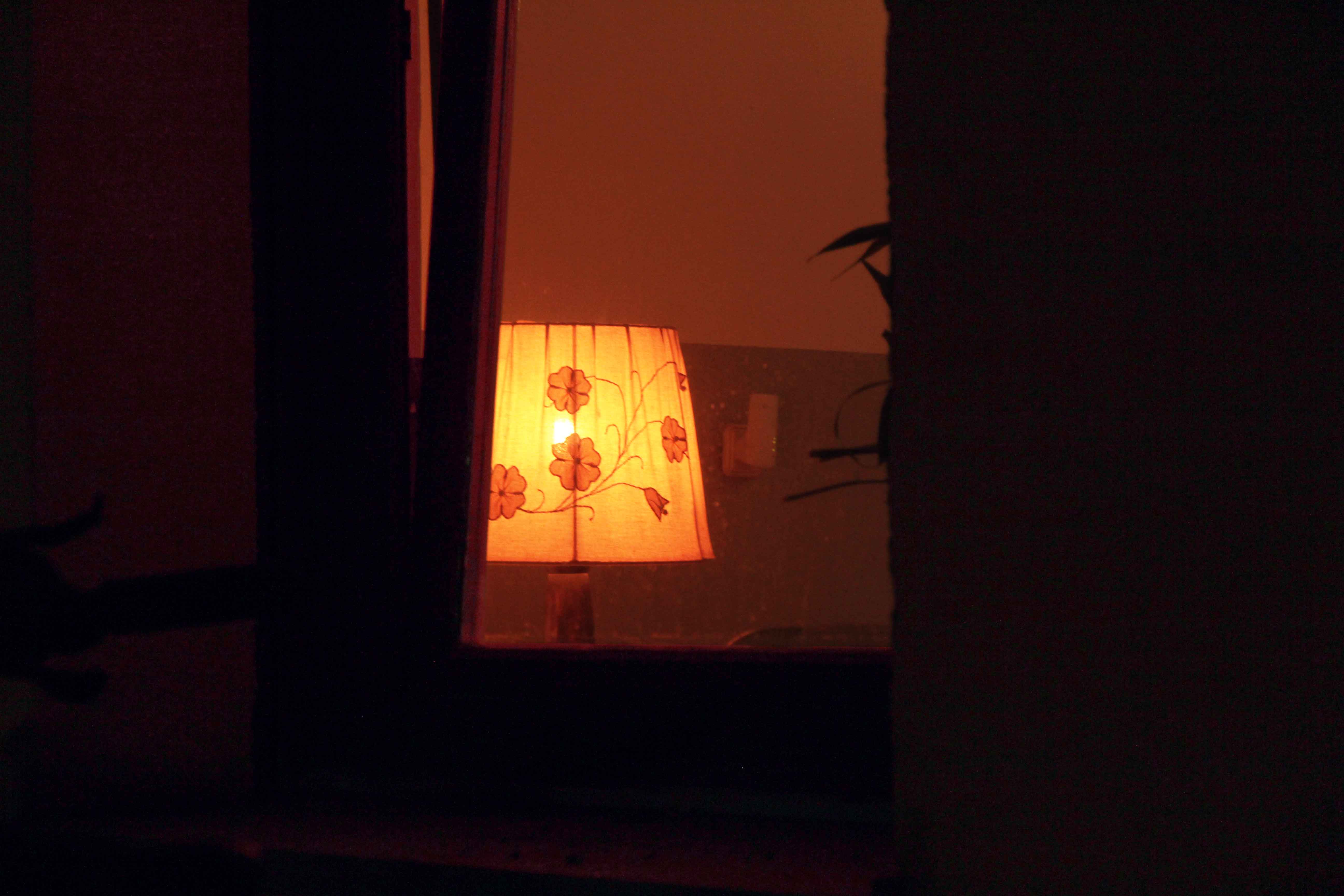 A lit lamp seen through a doorway at night